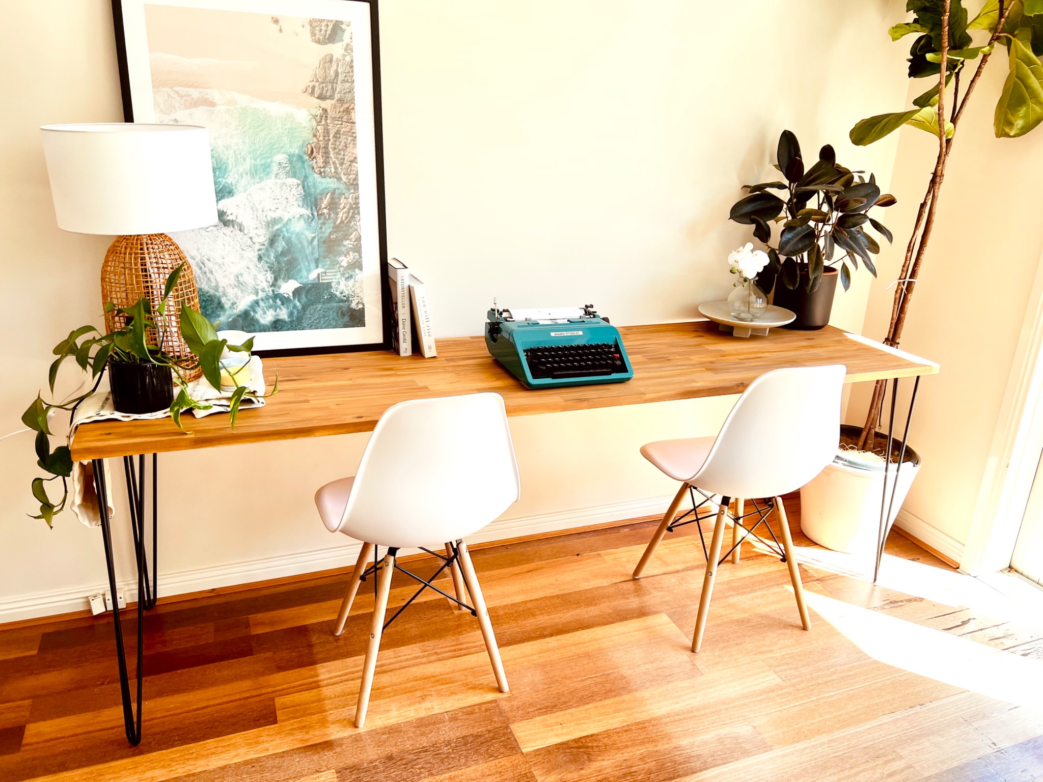 Long industrial dining table with two white chairs and typewriter
